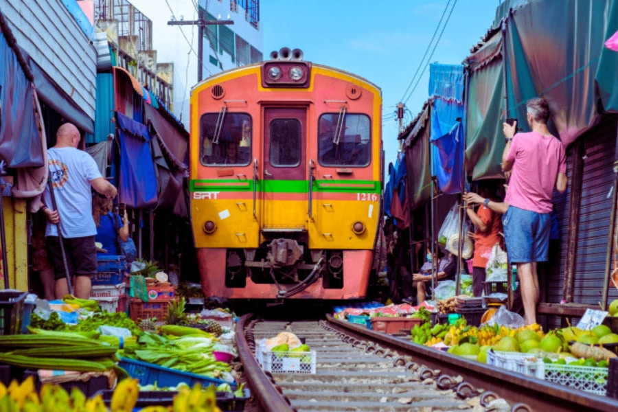 Train passing Maeklong Railway Market in Thailand with vendors – Auasia Travel